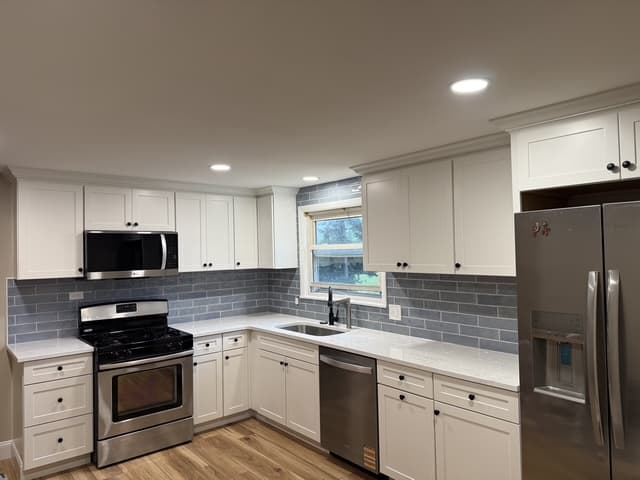 Bright white kitchen with gray subway backsplash and light wood flooring