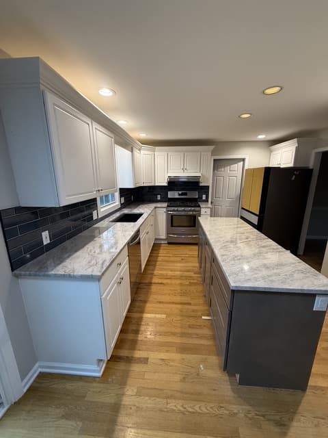 Kitchen with center island, marble-look counters and navy backsplash over hardwood floors